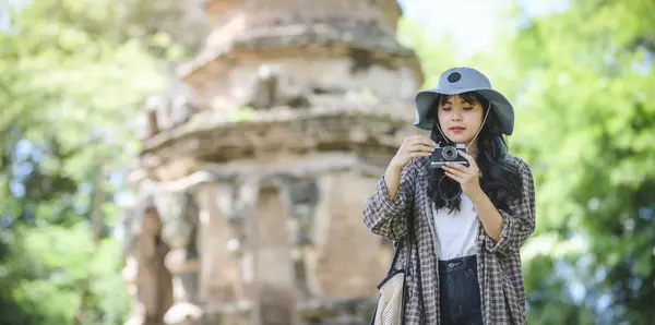 Молодая азиатская девушка фотографирует старый храм во время посещения древних исторических мест — стоковое фото