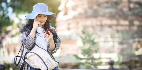 Genç sevimli Asya gezgin eski tarihi yerleri ziyaret ederken akıllı telefon üzerinde eski tapınağın ayrıntılarını kontrol — Stok fotoğraf