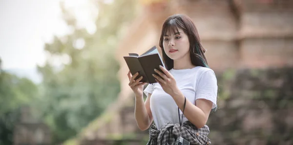 Jovem viajante do sexo feminino lendo o livro guia de viagem enquanto viaja em lugares históricos antigos — Fotografia de Stock