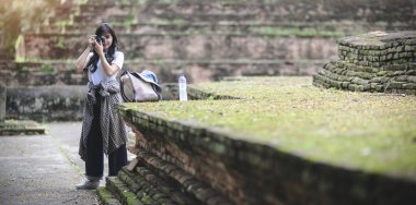 Genç asyalı kız antik tarihi yerleri ziyaret ederken eski tapınağın fotoğrafını çekerken 