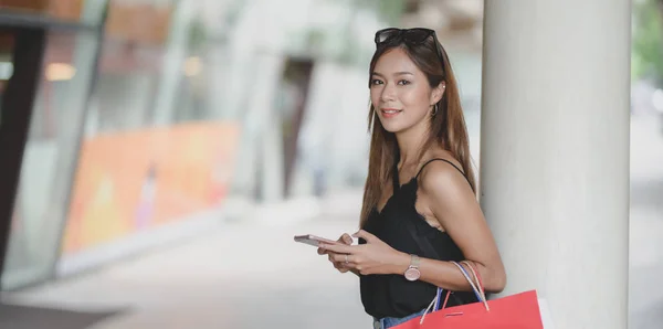 Portret van mooie vrouw glimlachend naar de camera terwijl staande buiten het winkelcentrum — Stockfoto