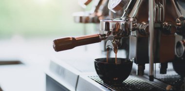 Espresso kahve makinesinden kahve dükkanındaki bir kahve fincanına dökülen espressonun yakın çekim görünümü 