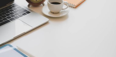 Fotokopi alanı ile beyaz ahşap masa üzerinde dizüstü bilgisayar, kahve fincanı ve ofis malzemeleri ile konforlu bir işyeri 