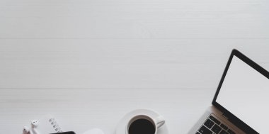 Fotokopi alanı ile beyaz ahşap masa üzerinde dizüstü bilgisayar, kahve fincanı ve ofis malzemeleri ile minimal işyeri üst görünümü 