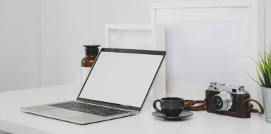 Beyaz ahşap masa üzerinde boş ekran dizüstü bilgisayar ve ofis malzemeleri ile Trendy fotoğrafçı işyeri 