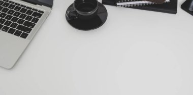 Beyaz masa arka plan üzerinde kopya alanı ile dizüstü bilgisayar ve kahve fincanı ile minimal işyeri üst görünümü