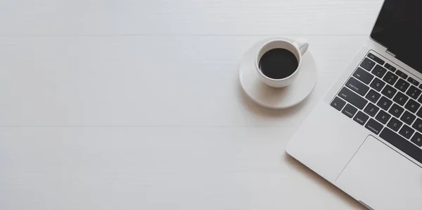 Vista superior del lugar de trabajo mínimo con ordenador portátil y una taza de café en la mesa de madera blanca — Foto de Stock