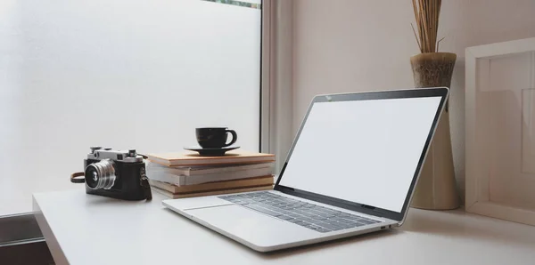 Минимум работы фотографа с открытым чистым экраном ноутбуком, винтажной камерой и чашкой кофе на белом деревянном столе — стоковое фото