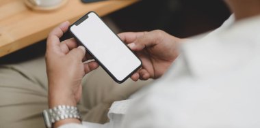 Sandalyede otururken elinde boş ekran akıllı telefonu tutan işadamının yakın görüntüsü 