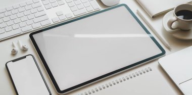Boş ekran tableti ve akıllı telefonun modern ofis tarzında ofis malzemeleri beyaz masada. 