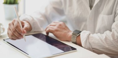 Modern ofis odasındaki tablete fikrini planlayan tutkulu serbest çalışanın yakın çekimi.