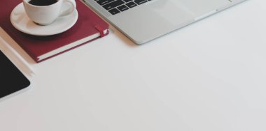 Laptop bilgisayar ve ofis malzemeleriyle beyaz ahşap masa üzerinde fotokopi alanı olan rahat bir iş yeri.