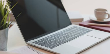 Açık dizüstü bilgisayarı, kahve bilgisayarı, kahve fincanı ve ofis malzemeleri olan modern rahat bir iş yeri.  