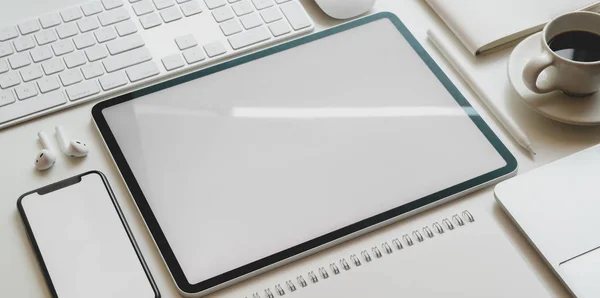 Vista superior de la tableta de pantalla en blanco y el teléfono inteligente con suministros de oficina en estilo de oficina moderno en escritorio blanco — Foto de Stock