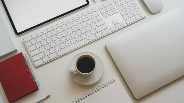 Vista superior del lugar de trabajo moderno con computadora portátil, taza de café y otros accesorios de oficina sobre fondo de mesa blanco —  Fotos de Stock