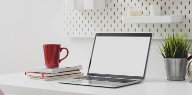 Boş bilgisayar, kırmızı kahve fincanı ve dekorasyonlu ofis malzemeleri olan rahat bir iş yeri. 
