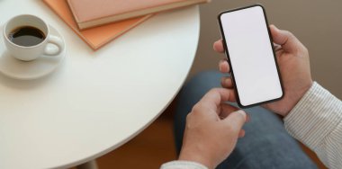 İş adamı rahat çalışma alanında boş ekran akıllı telefonu tutuyor 