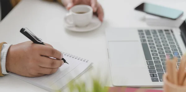 Uomo d'affari che lavora al suo progetto mentre scrive l'idea sul taccuino e beve una tazza di caffè — Foto Stock