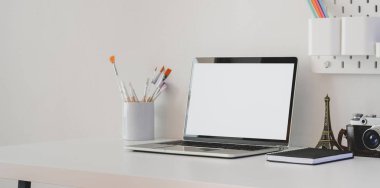 Boş ekran bilgisayarlı, kameralı ve beyaz masadaki dekorasyonlu minimal sanatçı çalışma alanı 
