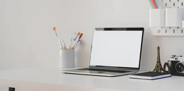 Espacio de trabajo mínimo del artista con ordenador portátil de pantalla en blanco con cámara y decoraciones en mesa blanca —  Fotos de Stock