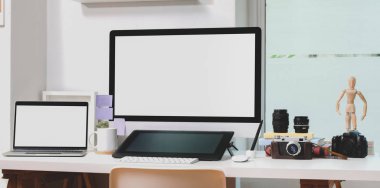 Boş ekran masaüstü bilgisayarı ve modern çalışma alanındaki ofis malzemeleriyle dizüstü bilgisayarı 