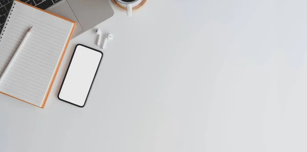 Comodo spazio di lavoro con smartphone a schermo bianco su scrivania in legno bianco con forniture per ufficio e copia — Foto Stock
