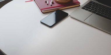 Beyaz ahşap masa üzerinde fotokopi alanı ve ofis malzemeleri olan çağdaş iş yerinin kırpılmış görüntüsü.