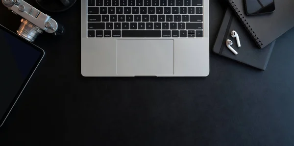 Bovenaanzicht van donker moderne werkplek met open laptop computer en kantoorbenodigdheden op zwart lederen bureauachtergrond — Stockfoto
