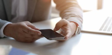 Profesyonel iş adamının ofisinde çalışırken akıllı telefonu taklit ettiği yakın plan görüntüler. 