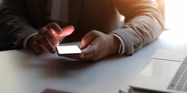 Ofisinde çalışırken elinde boş ekran akıllı telefon tutan işadamının yakın plan görüntüsü 