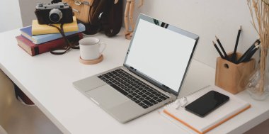 Modern ofis odasının açık ekran bilgisayarlı akıllı telefon ve ofis malzemeleriyle çekilmiş görüntüleri.  