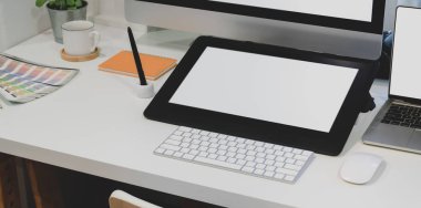 Ofis malzemeleri ile birlikte masaüstü bilgisayarı ile boş ekran dijital tableti olan tasarımcı iş yerinin yakın görüntüsü 