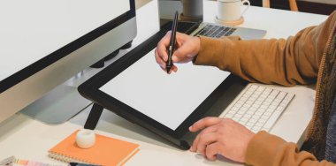 Erkek tasarımcının modern ofis odasındaki boş ekran dijital tabletle projesini düzenlerken görüntüsü kesilmiş. 