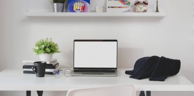 Mavi süveter ve ofis malzemeleri ile açık ekran dizüstü bilgisayarı olan minimal iş yeri 