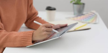 Genç bir kadının tabletle projesi üzerinde çalışırken görüntüsü kesilmiş. 