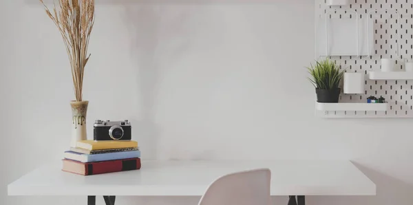 Espace de travail minime pour photographe avec caméra vintage et fournitures de bureau avec fond mural blanc — Photo