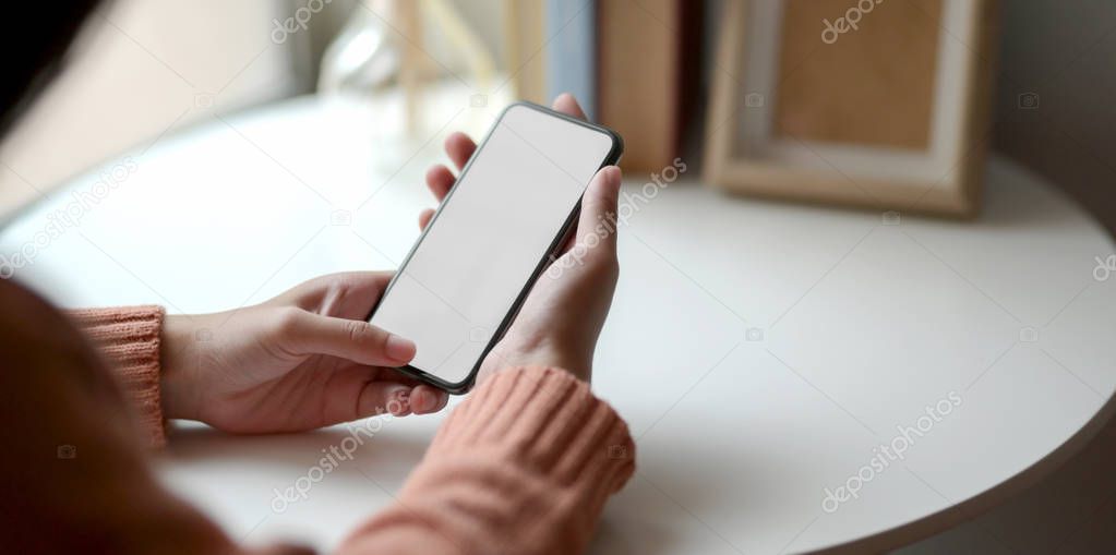 Close-up view of young female holding blank screen smartphone