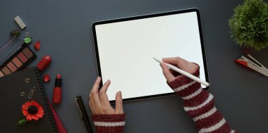 Kırmızı lüks konsepte sahip kadınsı çalışma alanı, boş ekran tabletle çalışan kadının üst görünümü 