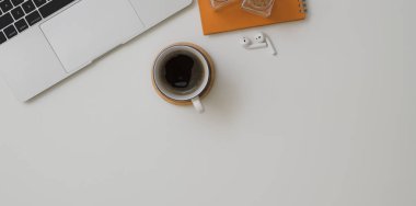 Dizüstü bilgisayarı, bir fincan kahve ve ofis malzemesi olan minimum çalışma alanı manzarası.