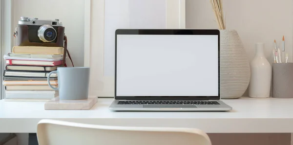 Computadora portátil de pantalla en blanco abierta en un espacio de trabajo mínimo con suministros de oficina y decoraciones —  Fotos de Stock