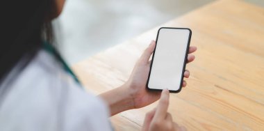Ofisindeki boş ekran telefonuna dokunan genç bayan doktorun yakın görüntüsü. 