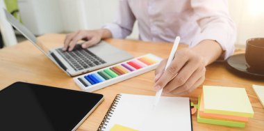 Genç profesyonel tasarımcının dizüstü bilgisayarını kullanarak projesini planlarken çekilmiş görüntüsü. 