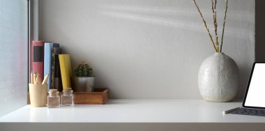 Boş ekran dijital tabletine sahip asgari çalışma alanı ve seramik vazo dekorasyonlarıyla kopyalama alanı 