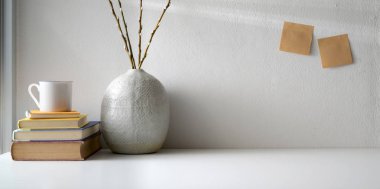 Beyaz masa ve beyaz duvar arkaplanı üzerinde seramik vazo süslemeleri ve kopya alanı olan en küçük çalışma alanı 