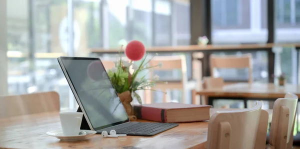 Comodo spazio di co-working con tablet con tastiera e libro, decorazioni e una tazza di caffè — Foto Stock