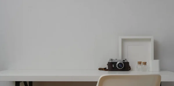 Ελάχιστος χώρος εργασίας με πλαίσια mock up και κάμερα σε λευκό φόντο τοίχου και λευκό τραπέζι — Φωτογραφία Αρχείου