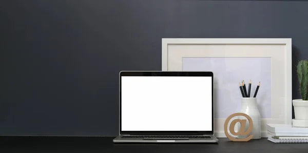 Minimal workspace with open blank screen laptop computer and mock up frame on black table and grey wall — Stock Photo, Image