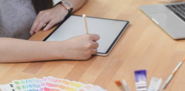 Genç bayan tasarımcının iş yerinde tablet kullanırken projesini planlarken yakın plan görüntüsü
