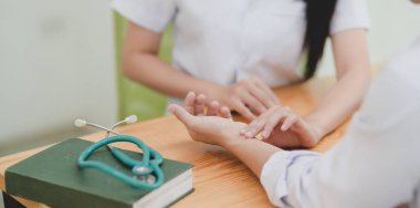 Hasta nabzını ölçen kadın doktor elini klinikte parçalıyor.