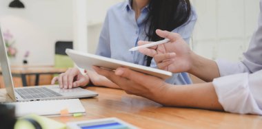 Bir grup profesyonel iş adamı tablet kullanırken şu anki projelerini tartışıyor.